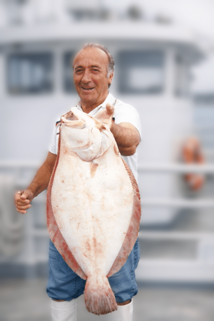 Man holding a big summer flounder. Blurry Boat in the background  